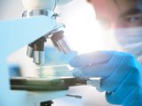 A scientist placing a slide under a microscope
